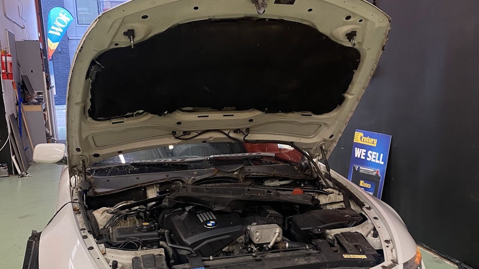 A car with its bonnet up being inspected in a South End Motors workshop